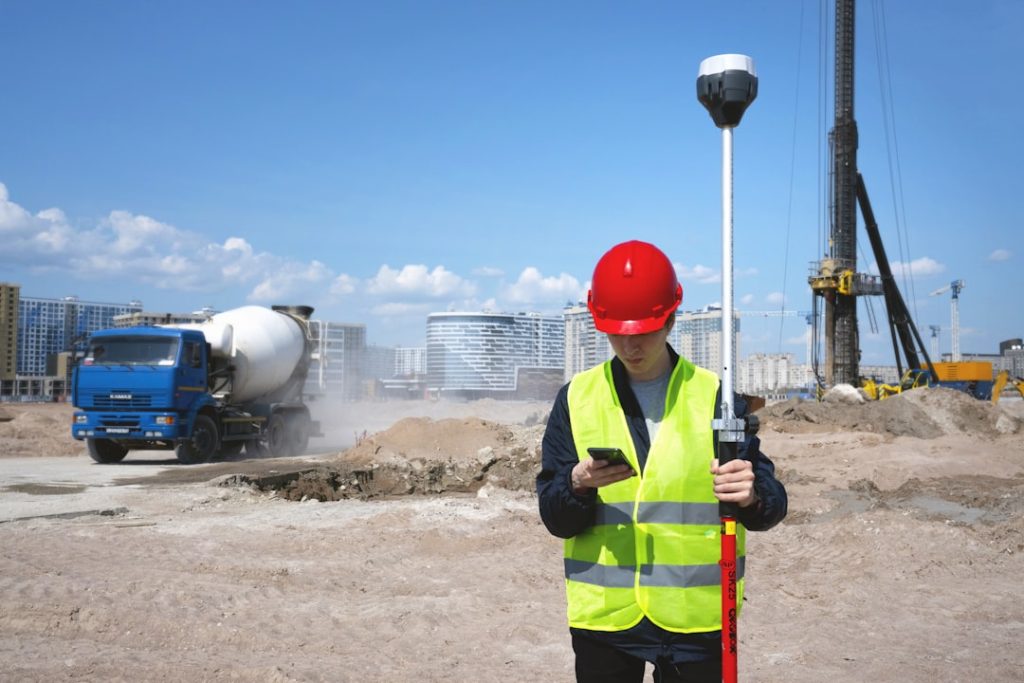 man-in-black-and-yellow-jacket-wearing-red-helmet-holding-black-and-white-stick-pdjpa1yeonw Precise positioning on construction site